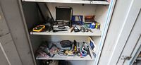 Cabinet shelves with assorted hand tools and drill bit set