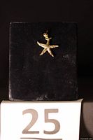 Front view of 14K gold starfish charm on stand