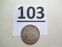 Coin with lot number card showing obverse partially