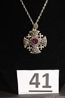 Pendant on chain against black background, full view