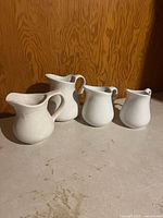 Group shot of four white ceramic creamers
