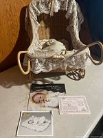 Overall view of wicker stroller with doll, bedding and paperwork