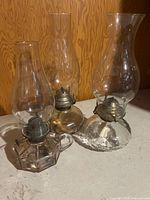 Group shot of three clear glass coal oil lamps