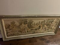 Full view of framed crewel piece leaning against wall