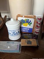 Group shot showing milk glass jar, flower press, Norwex cloths, Norwex glasses cleaner, tube of bows