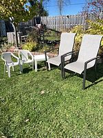 Full lot outdoors: two grey sling chairs, two white kids chairs, white side table