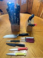 Overall lot showing two wooden knife blocks filled with knives and additional loose knives on table