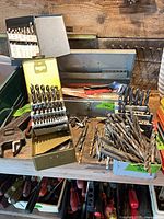 Wide view of assorted drill bits, index boxes, storage tray