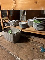 Stacks of plates and cups on shelf plus basket of additional pieces