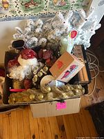 Box of mixed Christmas decor items including Santa head, gold wreath, ornaments, artificial white branches