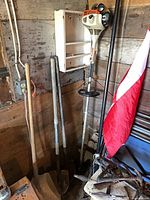 STIHL trimmer hanging beside pole pruner and shovels in corner