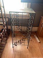 Full view of metal plant stand showing grid frame and vine leaves