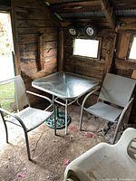 Full view of table, two chairs and umbrella base inside shed