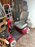 Full view of red Pride Victory 4-wheel scooter with gray seat, front and rear baskets visible