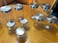 Nine glass jars of varying sizes with metal lids
