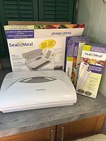 Vacuum sealer appliance front with two boxes of rolls and original appliance carton
