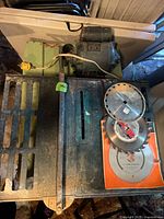 Top view of table saw, fence bar, two extra blades with packaging visible