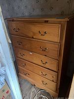 Front view of wooden 5-drawer dresser with brass-tone pulls