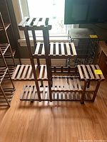 Full view of wooden slatted plant stand showing six shelves and casters