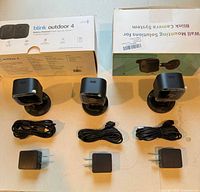 Three indoor Blink cameras with cables, adapters; sealed Blink Outdoor 4 box; sealed wall mount kit