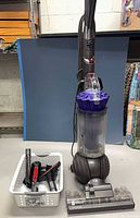 Full view of Dyson DC41 Animal vacuum with basket of attachments