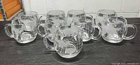 Front view showing eight mugs and creamer displaying etched map pattern
