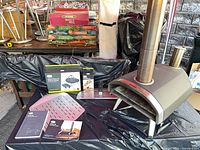 Ooni Fyra 12 oven with accessories and boxed cover and thermometer visible