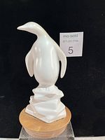 Full view of white ceramic penguin on walnut base