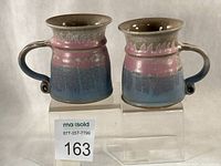 Front view of both gradient glaze mugs on acrylic risers with lot number visible