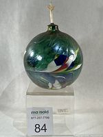 Full view of spherical multicolour glass oil lamp on stand with wick visible