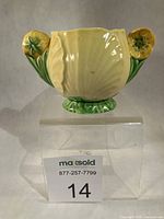Front view of Carlton Ware Buttercup sugar bowl on clear riser