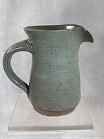 Profile view of stoneware creamer showing glaze and handle