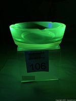 Ashtray glowing vivid green under UV light on display stand