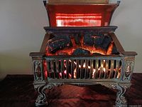 Front view of lit Magicoal heater showing hinged lid open and glowing coals