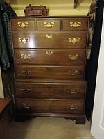 Front view of tall six-drawer dresser showing wood finish and brass hardware