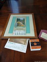 All items laid out on table: framed calendar, boxed Ideal pad, red desk calendar, loose 1974 page