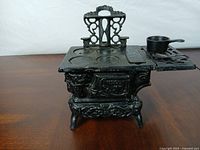 front view of cast iron miniature stove showing oven door and pot
