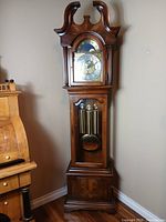 Full view of grandfather clock showing bonnet, dial, case, and base