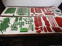 Full layout of green and red Meccano parts with hardware bags visible