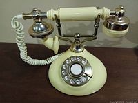 Front view of cream rotary telephone showing dial and handset on cradle