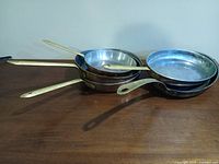 Five copper frying pans nested showing brass handles