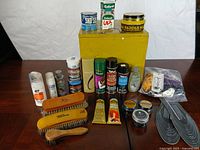 Group shot of yellow box, polishes, sprays, brushes, laces, insoles