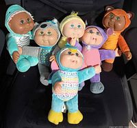Six assorted Cabbage Patch Kids Cuties plush dolls grouped on chair