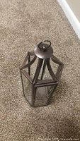 Hexagonal metal and glass lantern lying on carpet