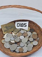Basket holding assorted foreign coins and brass belt buckle