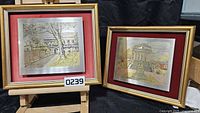 Both framed etched metal artworks on display stand