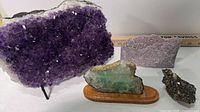 Front view of amethyst slice on stand with three additional mineral specimens