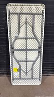 Full underside view of folded 6ft Uline table showing leg frame