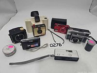 All items arranged together showing six cameras, film tin and film canister
