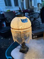 Full lamp illuminated showing base, shade, beaded fringe
